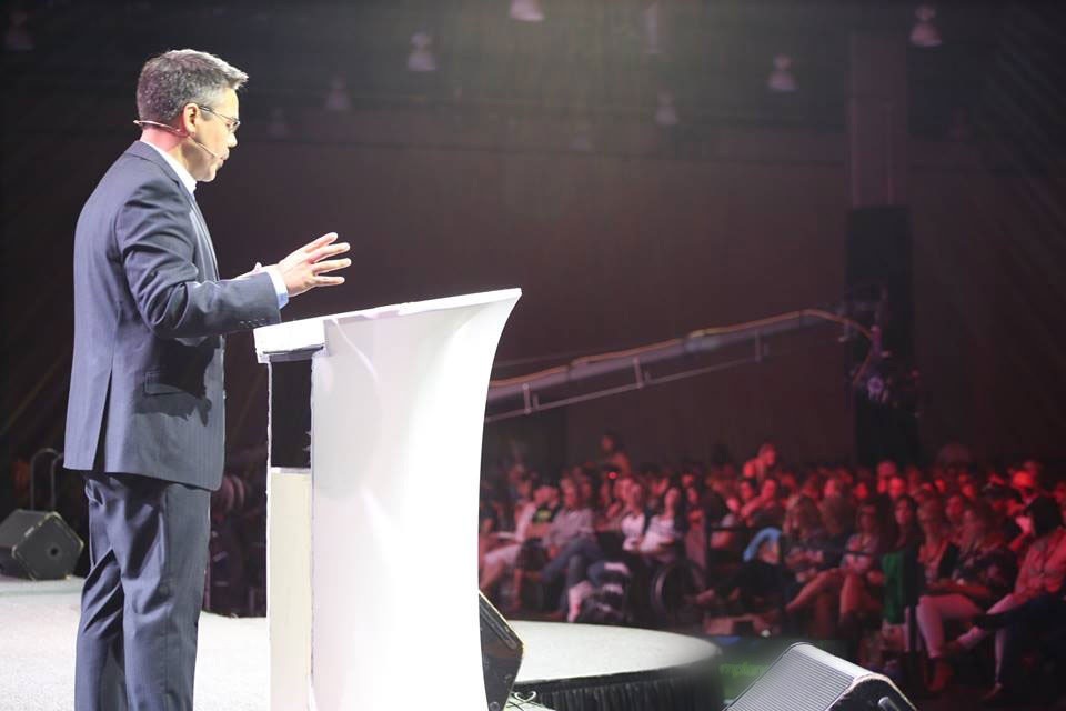 Chris &ldquo;Shmiddy&rdquo; Schmidt speaking on stage to a full room